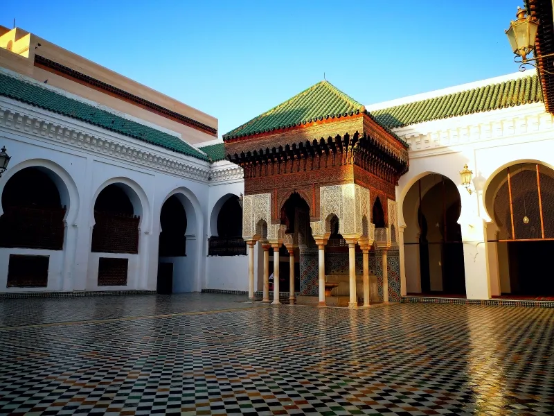 Courtyard of a building featuring arches and a green roof, showcasing attractions in Fez.