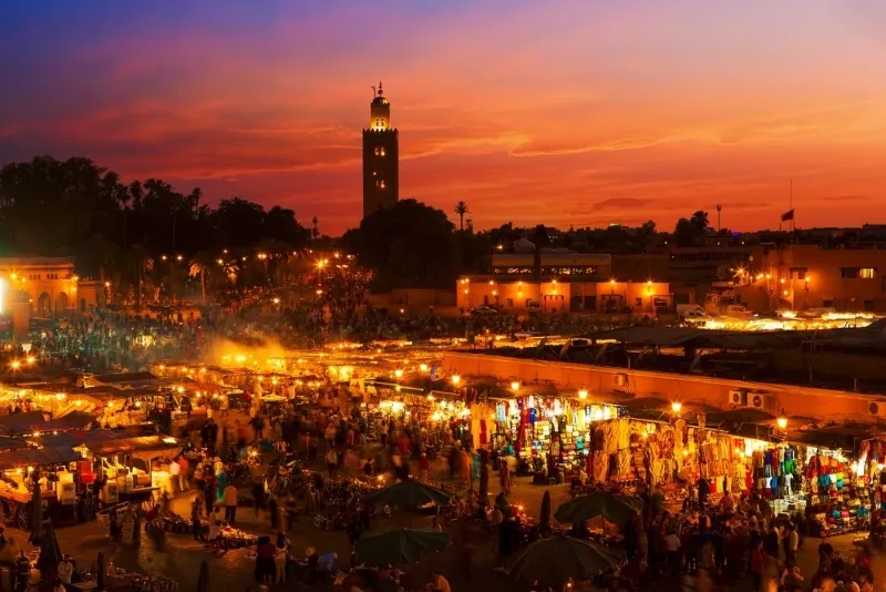 Marrakech skyline at dusk, showcasing illuminated buildings and a vibrant sky, capturing the essence of the city.