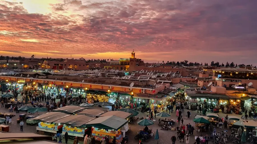 Sunset casting warm hues over the skyline of Marrakech, highlighting the city's unique architecture and vibrant atmosphere.