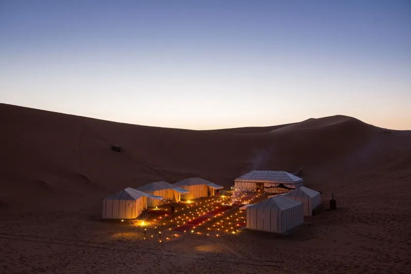 A lit tent in the desert, showcasing a cozy atmosphere for desert tours Marrakech.