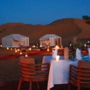 A candlelit dinner table arranged in the desert, highlighting an enchanting atmosphere for Marrakech desert tours.