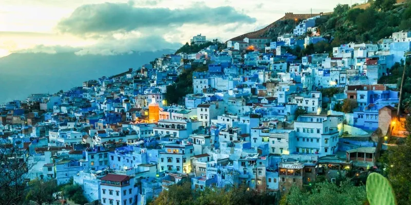 A scenic view of Chefchaouen, Morocco, showcasing its iconic blue buildings and mountainous backdrop.