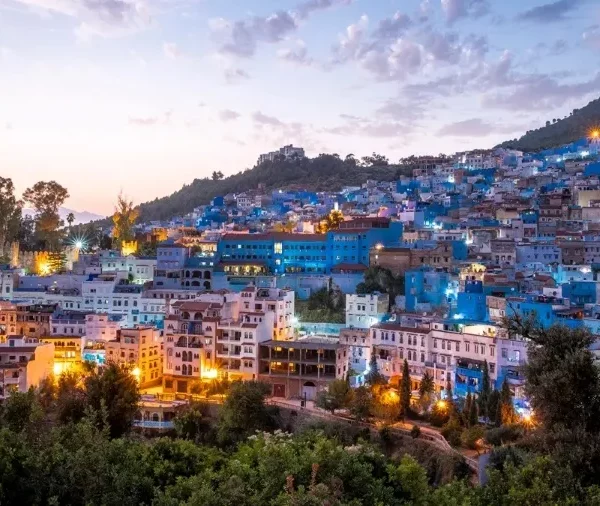 A scenic view of Chefchaouen, Morocco, showcasing its iconic blue buildings and mountainous backdrop.