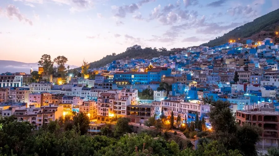 A scenic view of Chefchaouen, Morocco, showcasing its iconic blue buildings and mountainous backdrop.
