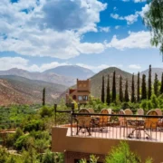Scenic view from a hotel terrace in the Moroccan mountains, showcasing lush greenery and distant peaks under a clear sky.
