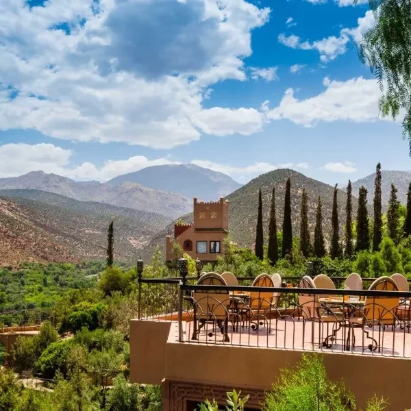 Scenic view from a hotel terrace in the Moroccan mountains, showcasing lush greenery and distant peaks under a clear sky.
