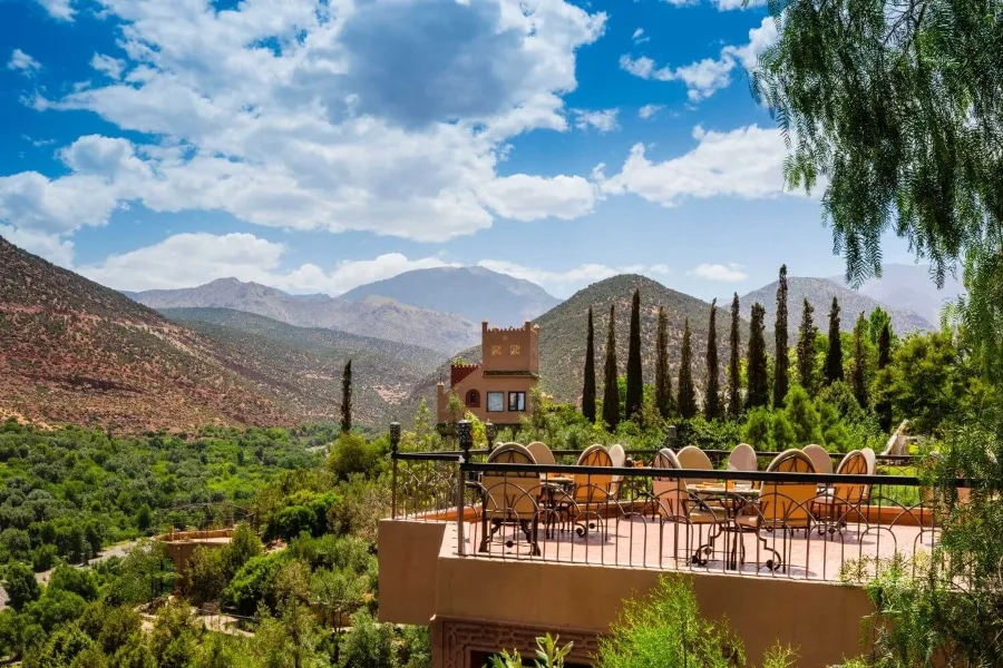 Scenic view from a hotel terrace in the Moroccan mountains, showcasing lush greenery and distant peaks under a clear sky.